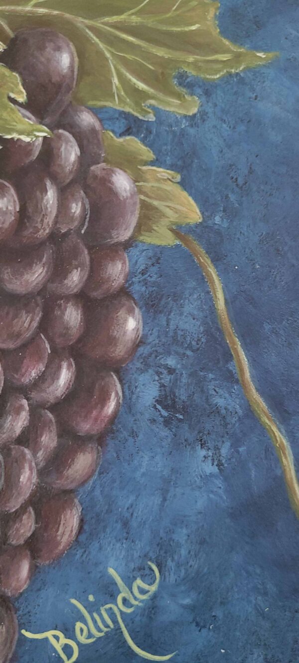 Painting of a lush grape cluster with green leaves against a deep blue background by artist Belinda Buckler